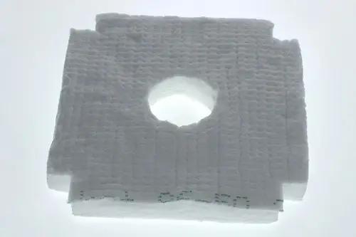 Weißes Isoliermaterial mit rechteckiger Form und zentralem Loch, auf hellem Hintergrund. Zu erkennen ist die Struktur des Materials, das möglicherweise von Bosch stammt.